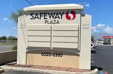 A large sign for safeway plaza in a parking lot