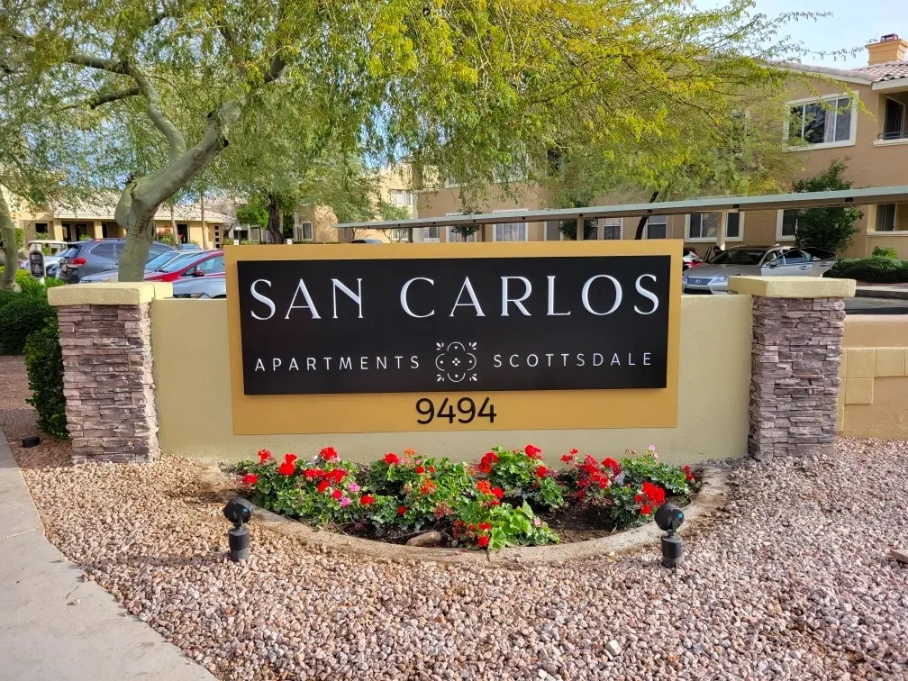 A sign for san carlos apartments sits in front of a building