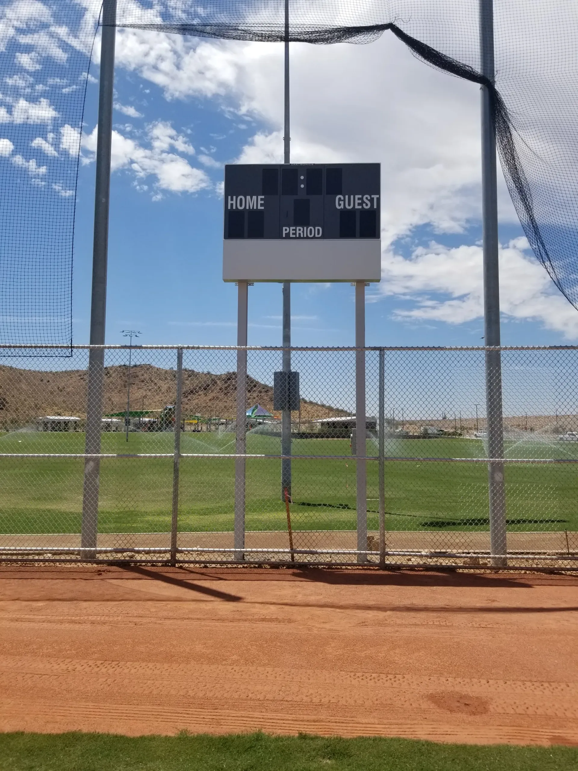 A baseball field with a scoreboard that says guest on it