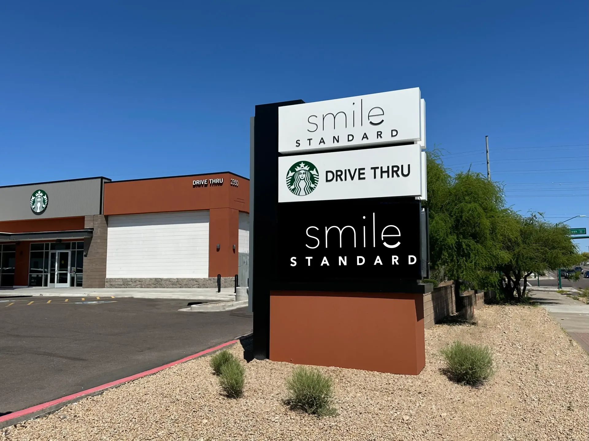 A starbucks drive thru and a smile standard sign in front of a building