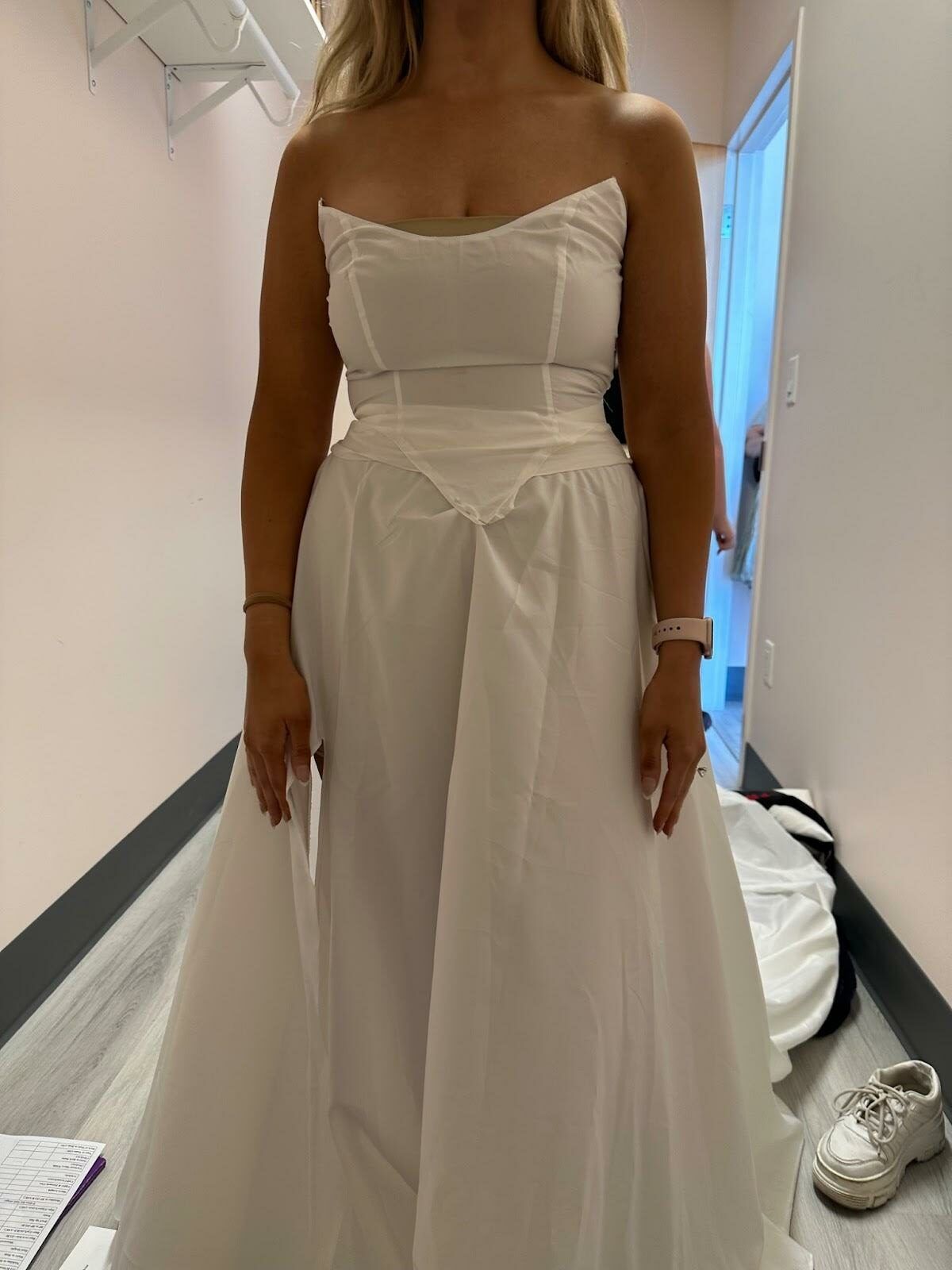A woman in a white wedding dress is standing in a hallway.