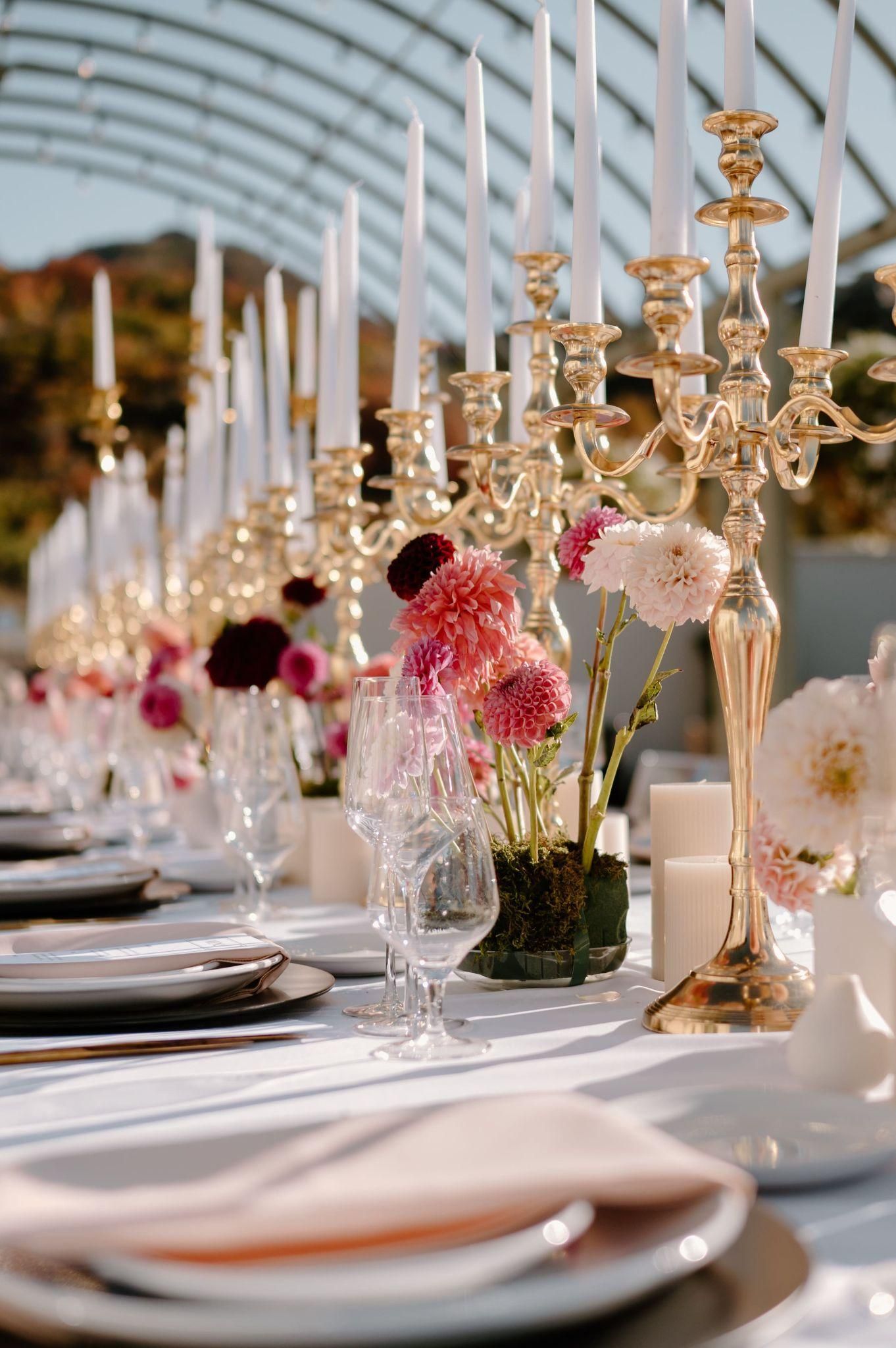 A long table with plates , candles , and flowers on it.