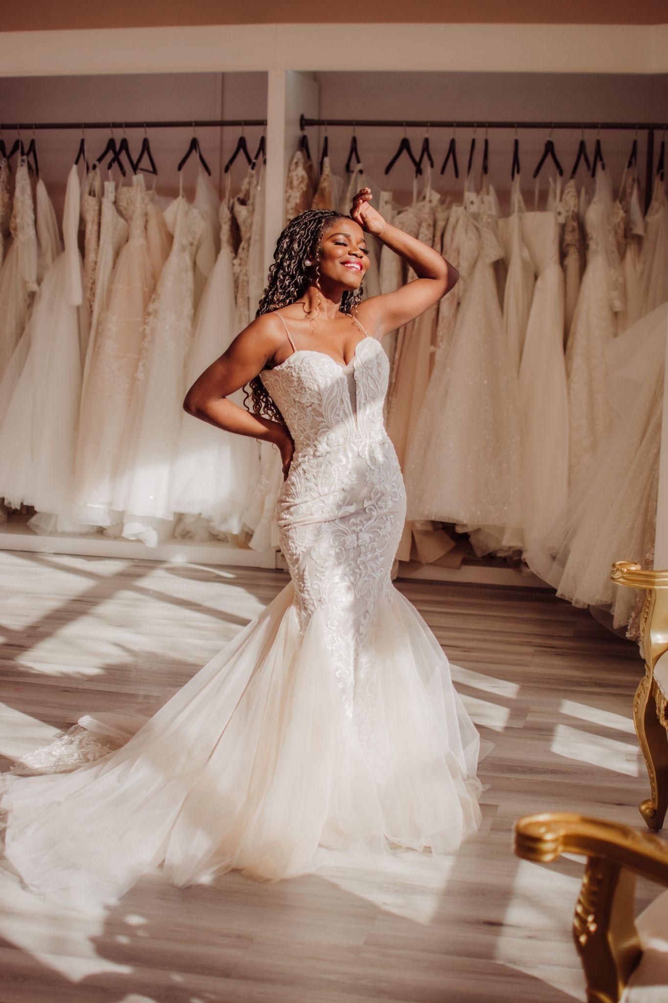 A woman in a wedding dress is standing in a bridal shop.