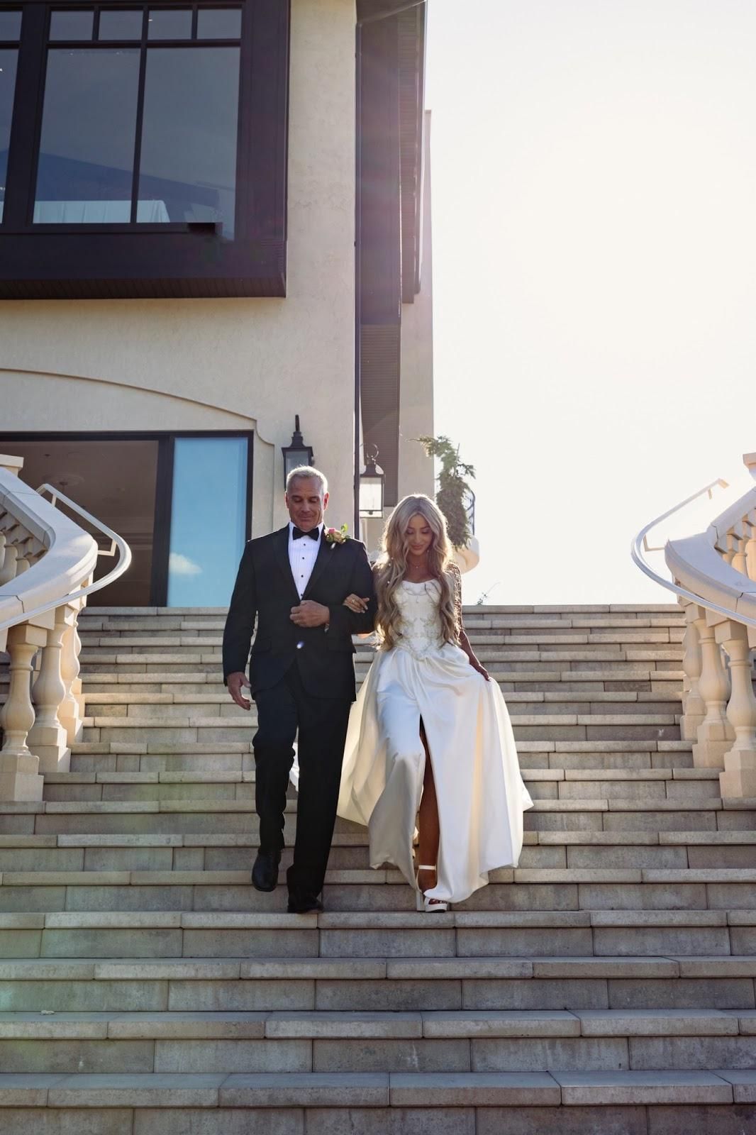 A bride and groom are walking down a set of stairs.