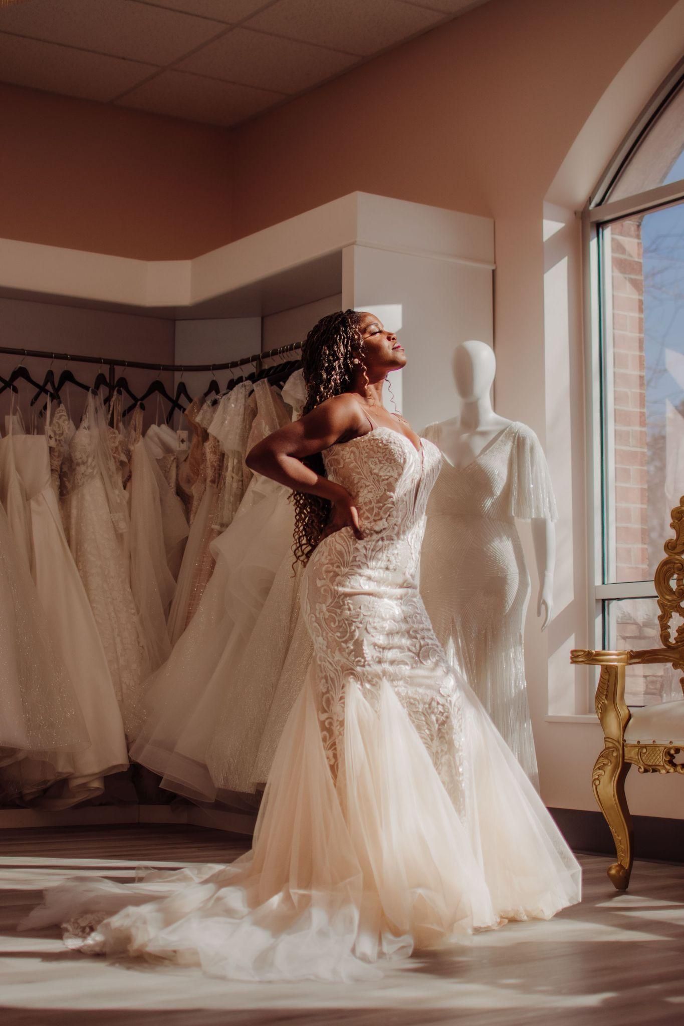 A woman in a wedding dress is standing in a bridal shop.