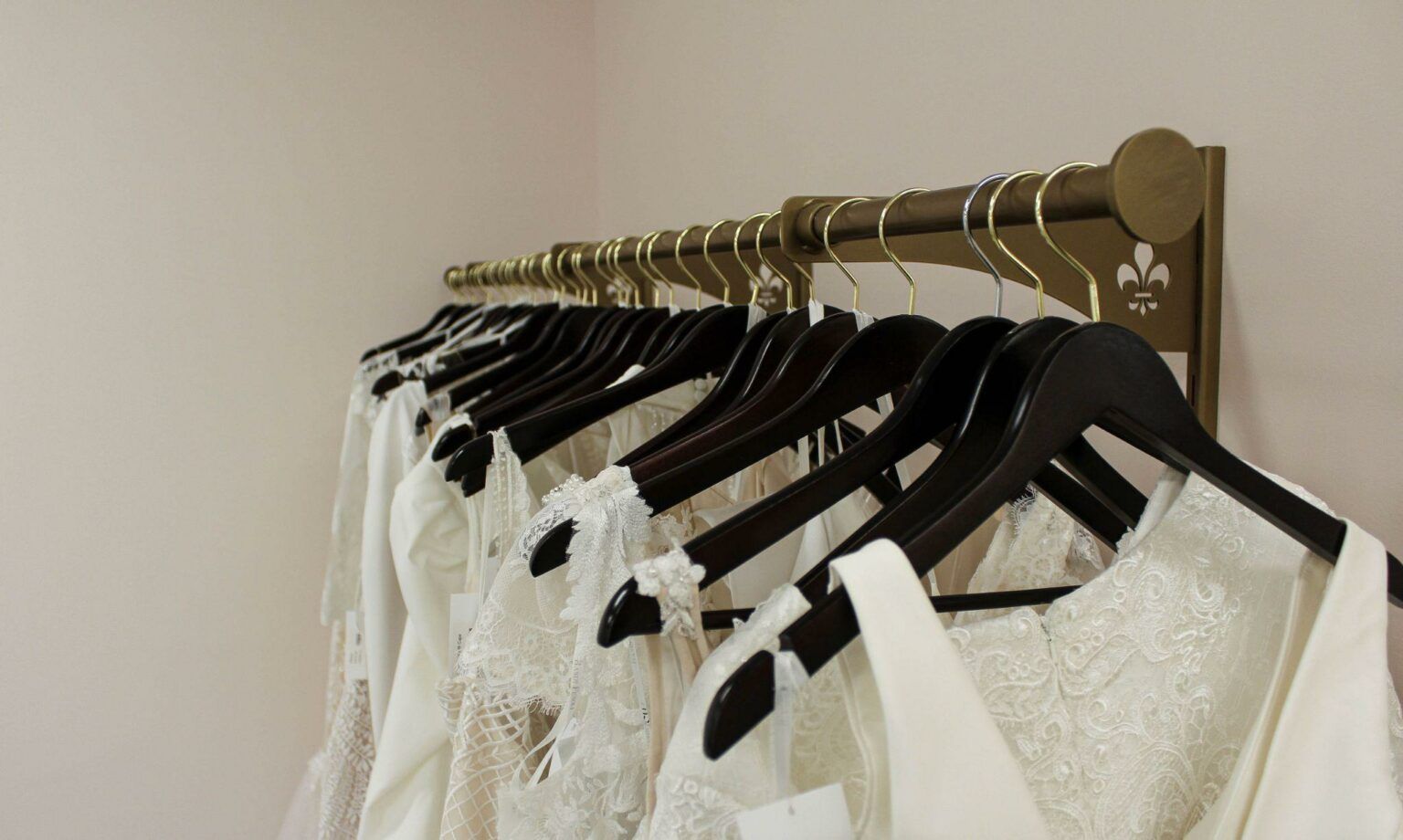 A row of white dresses are hanging on a rack.