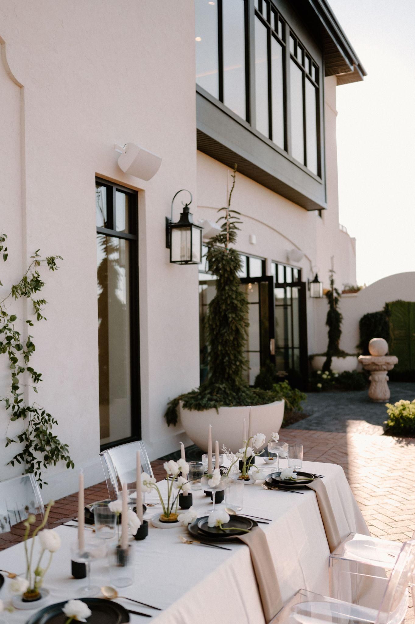 A long table set for a wedding reception in front of a white building.
