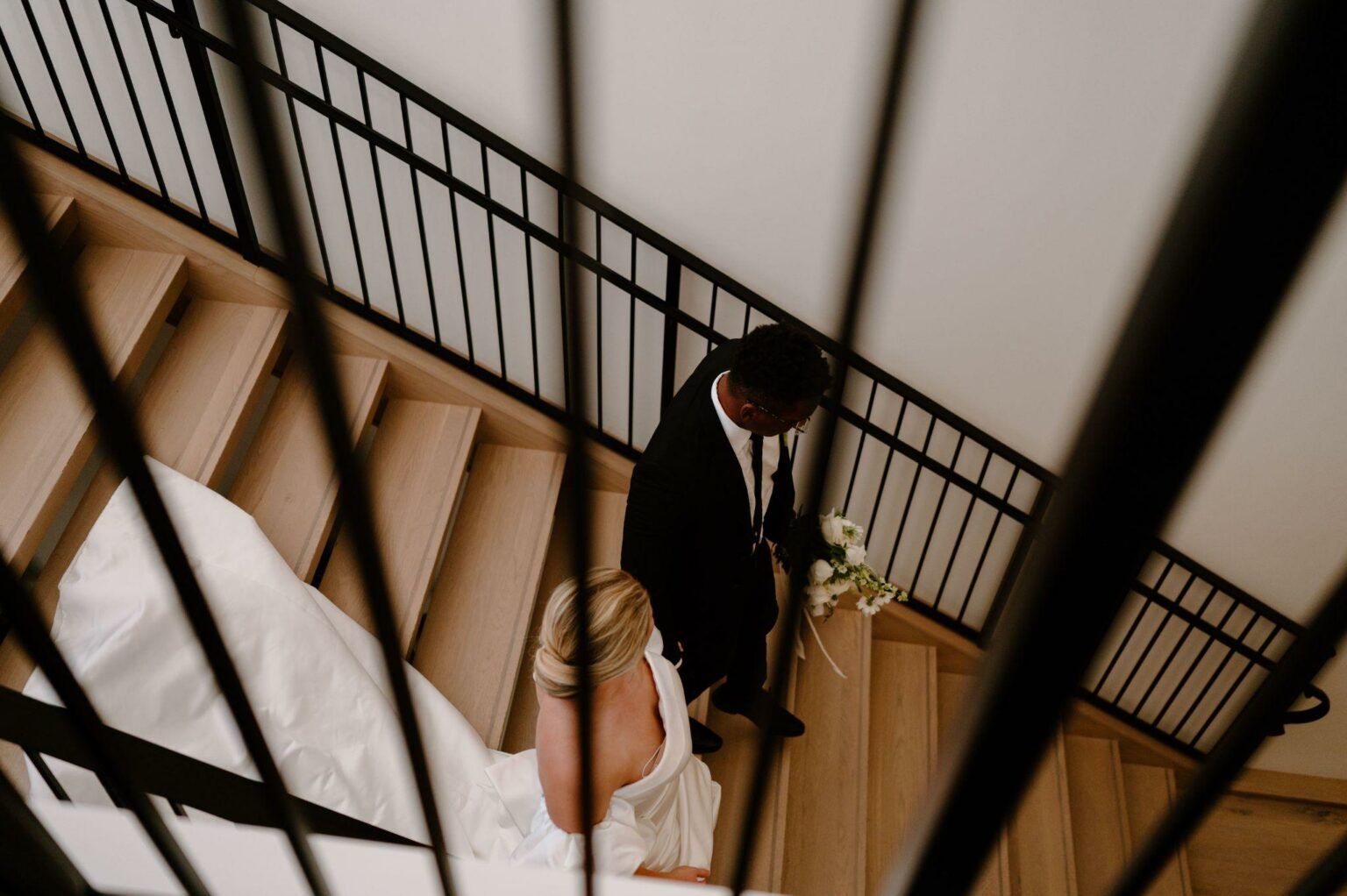 A bride and groom are walking down a set of stairs.