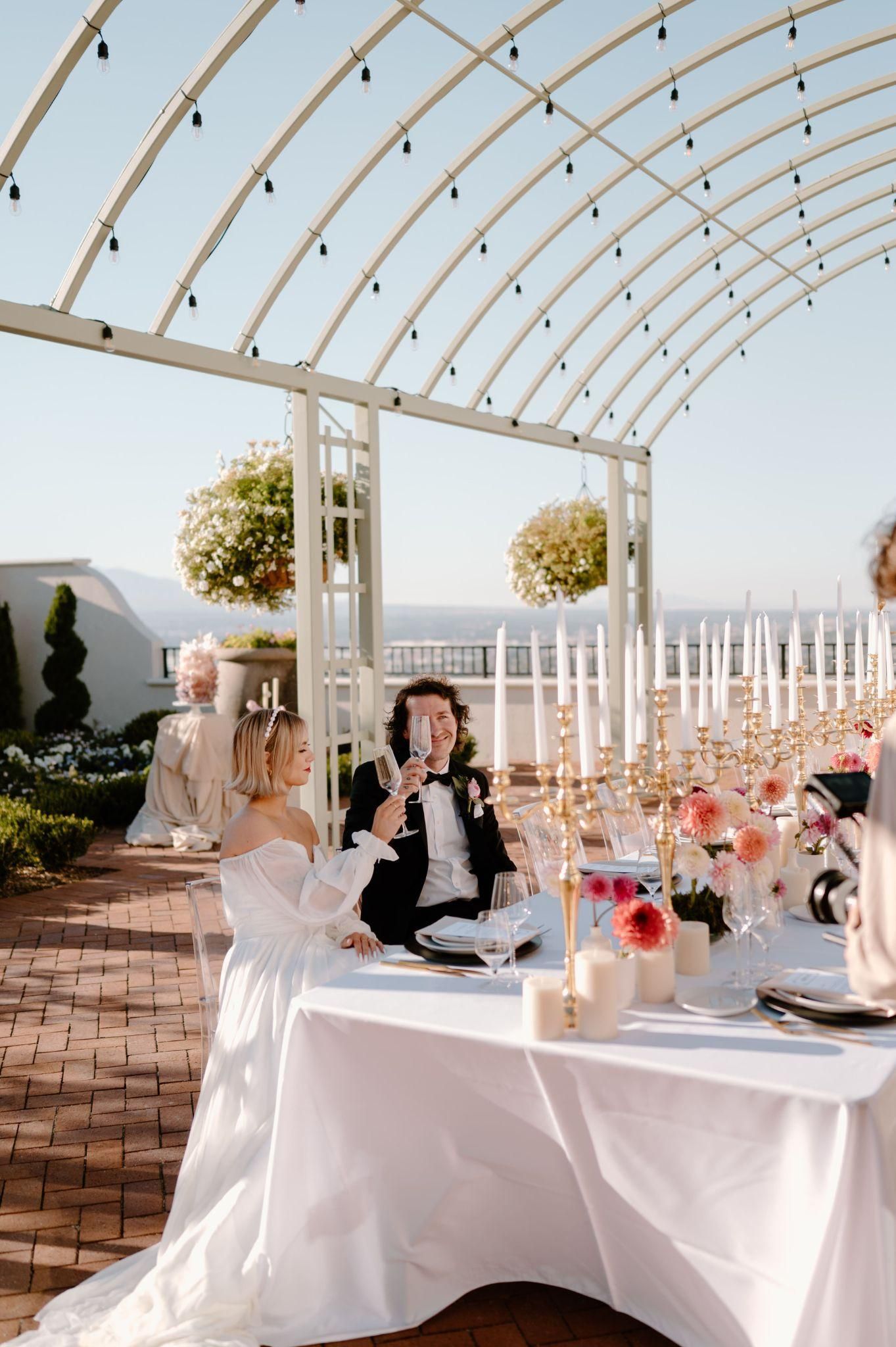 A bride and groom are sitting at a table at a wedding reception.