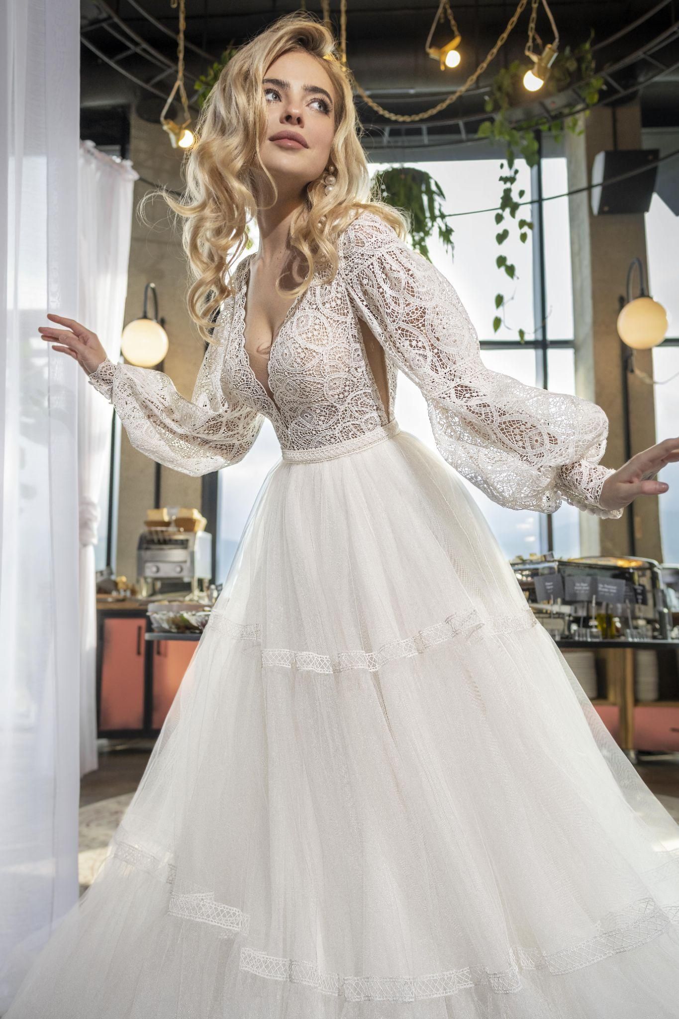 A woman in a wedding dress is standing in front of a window.