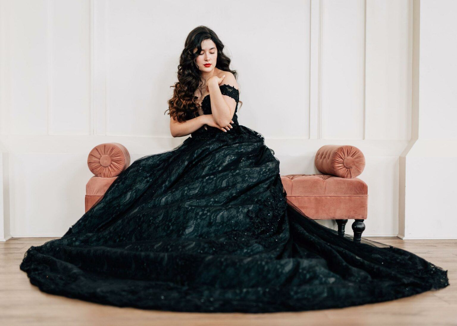 A woman in a long black dress is sitting on a bench.
