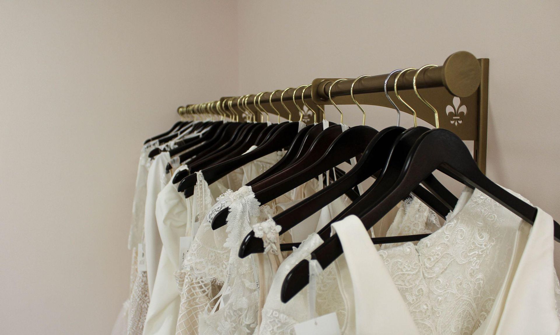 A row of white dresses are hanging on a rack.