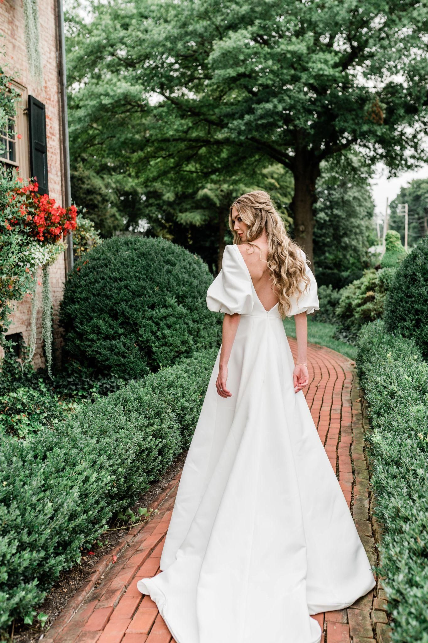 A woman in a white wedding dress is walking down a brick path.