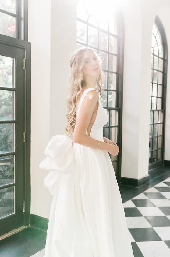 A woman in a white wedding dress is standing in a hallway.