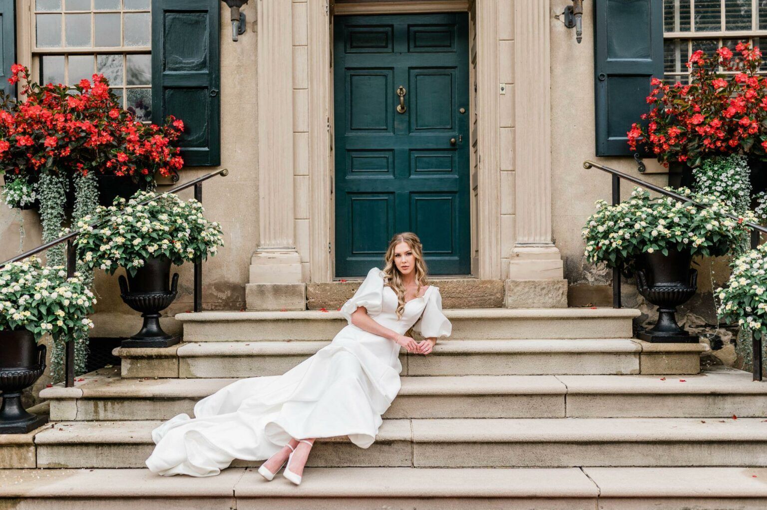 A woman in a wedding dress is sitting on the steps of a building.