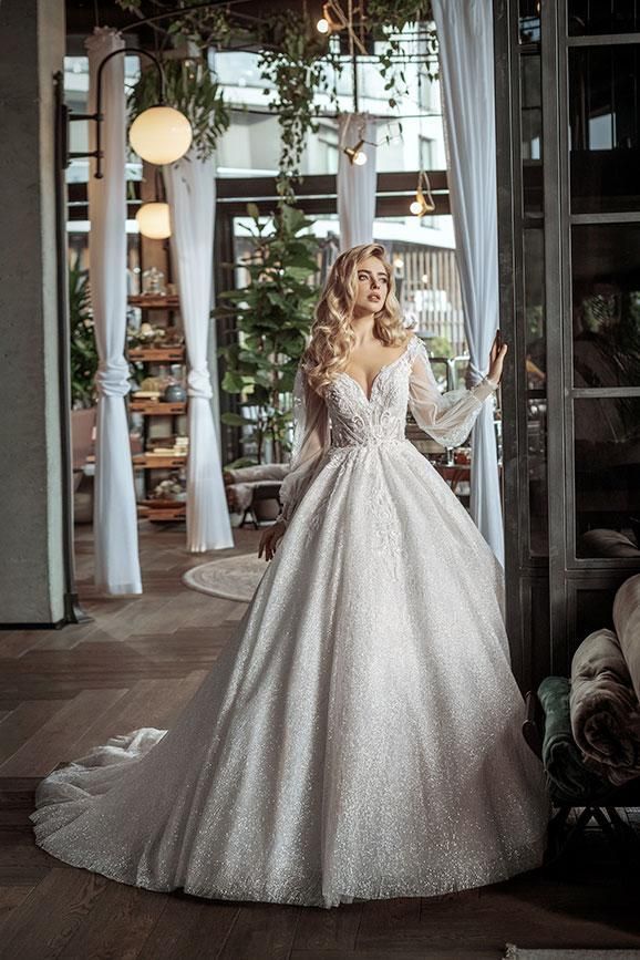 A woman in a wedding dress is standing in front of a window in a room.