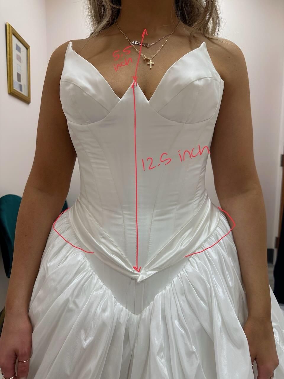 A woman is wearing a white dress with measurements written on it
