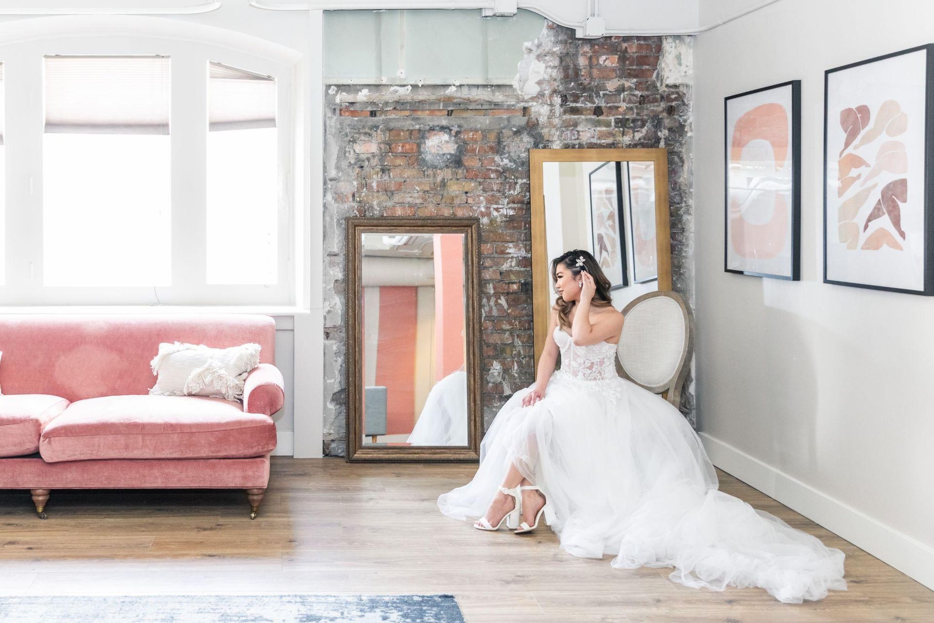 A woman in a wedding dress is sitting on a couch in a living room.