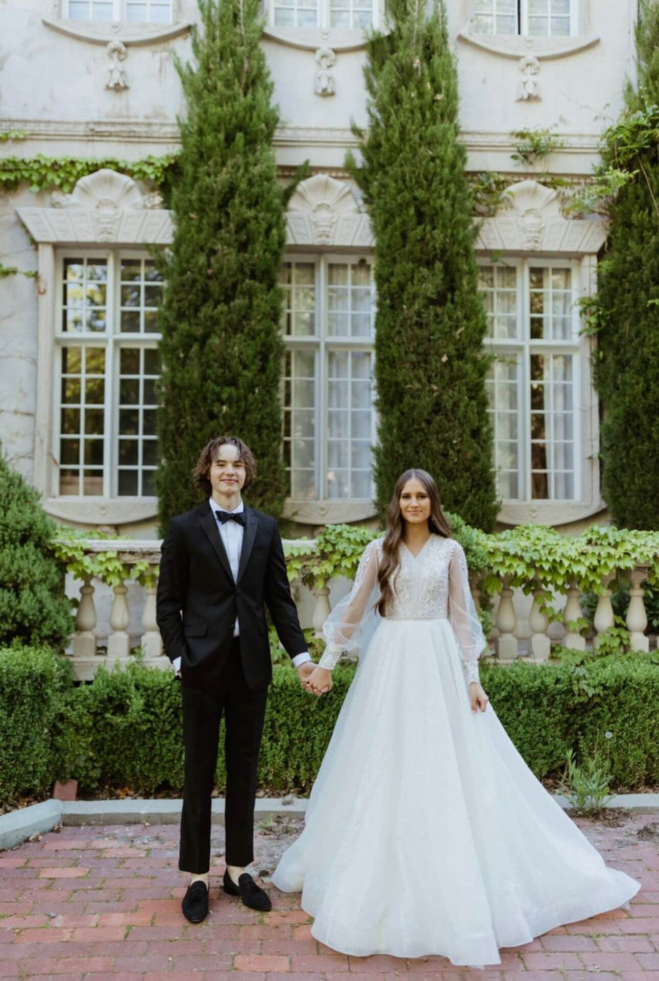 A bride and groom are holding hands in front of a building.