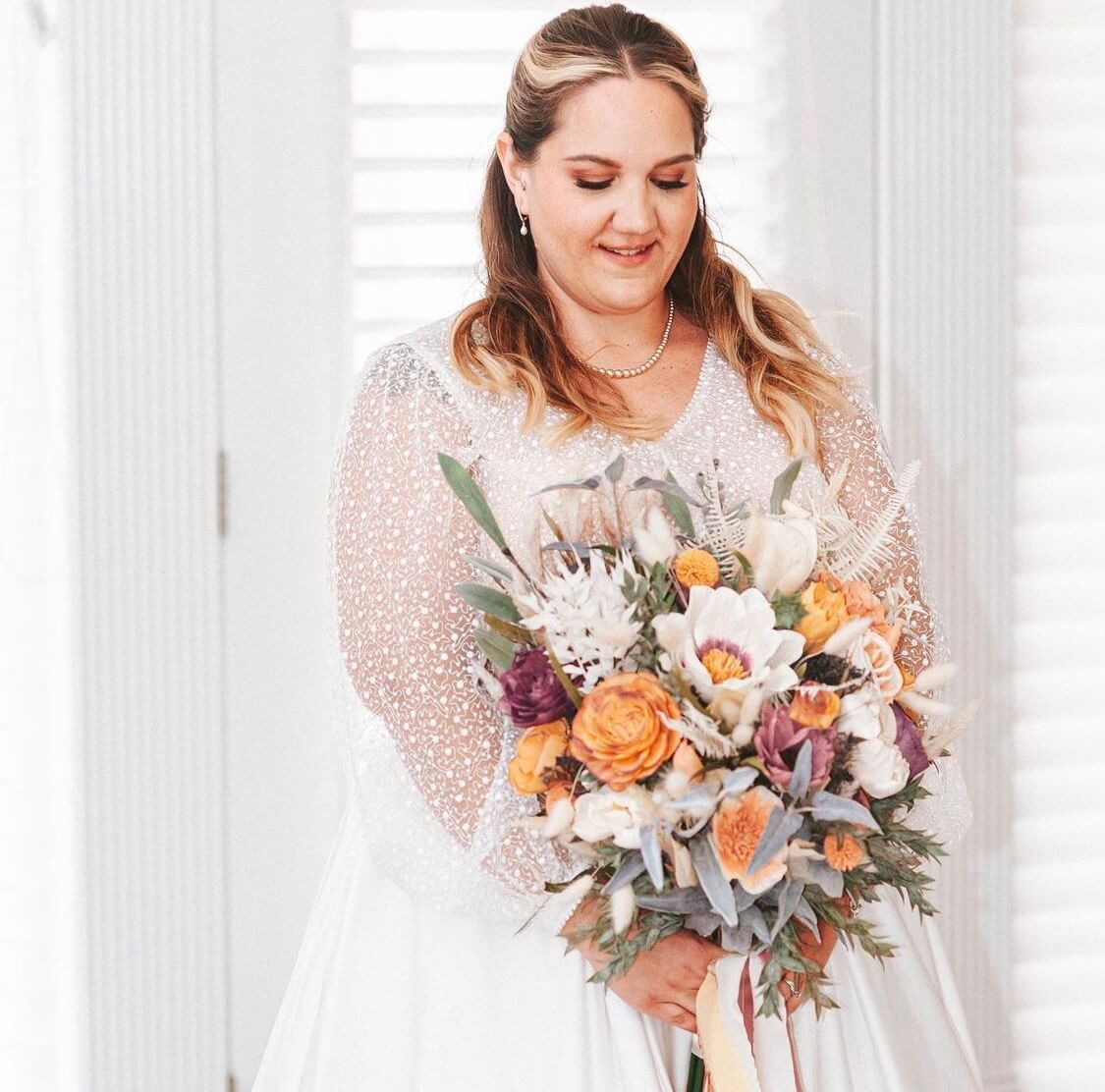 A bride in a white dress is holding a bouquet of flowers.