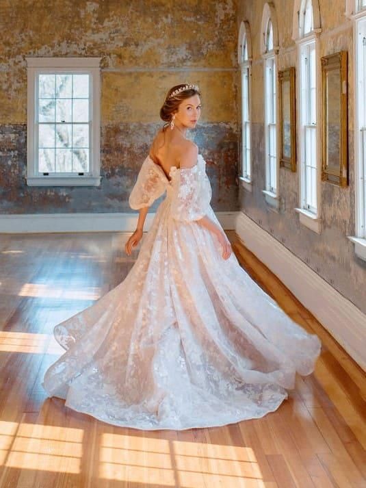 A woman in a wedding dress is standing in a hallway.