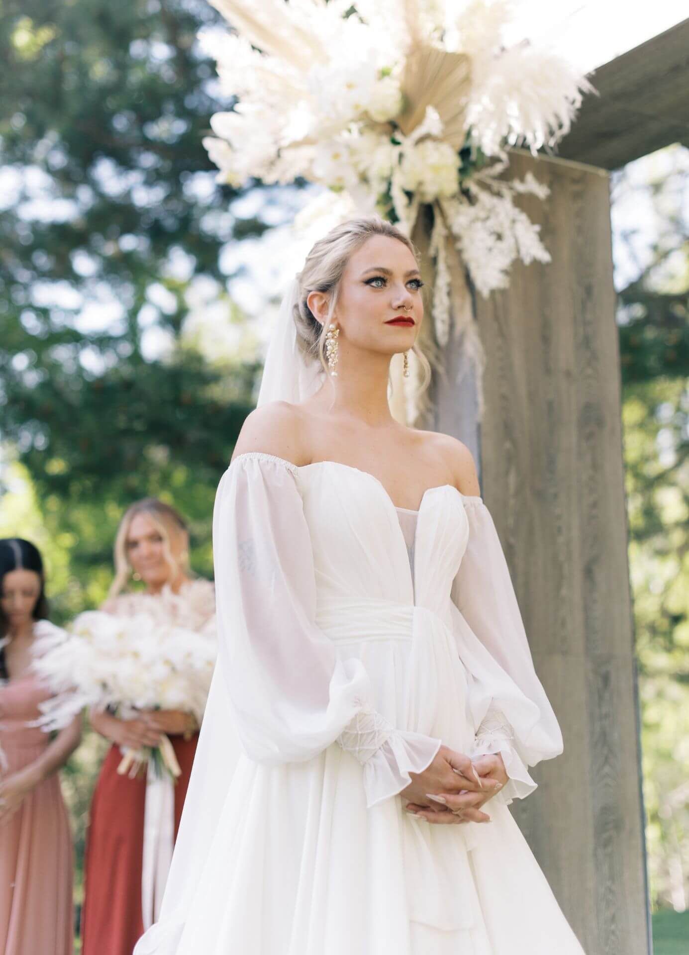 The bride is wearing her customized white wedding dress with long sleeves and a veil.