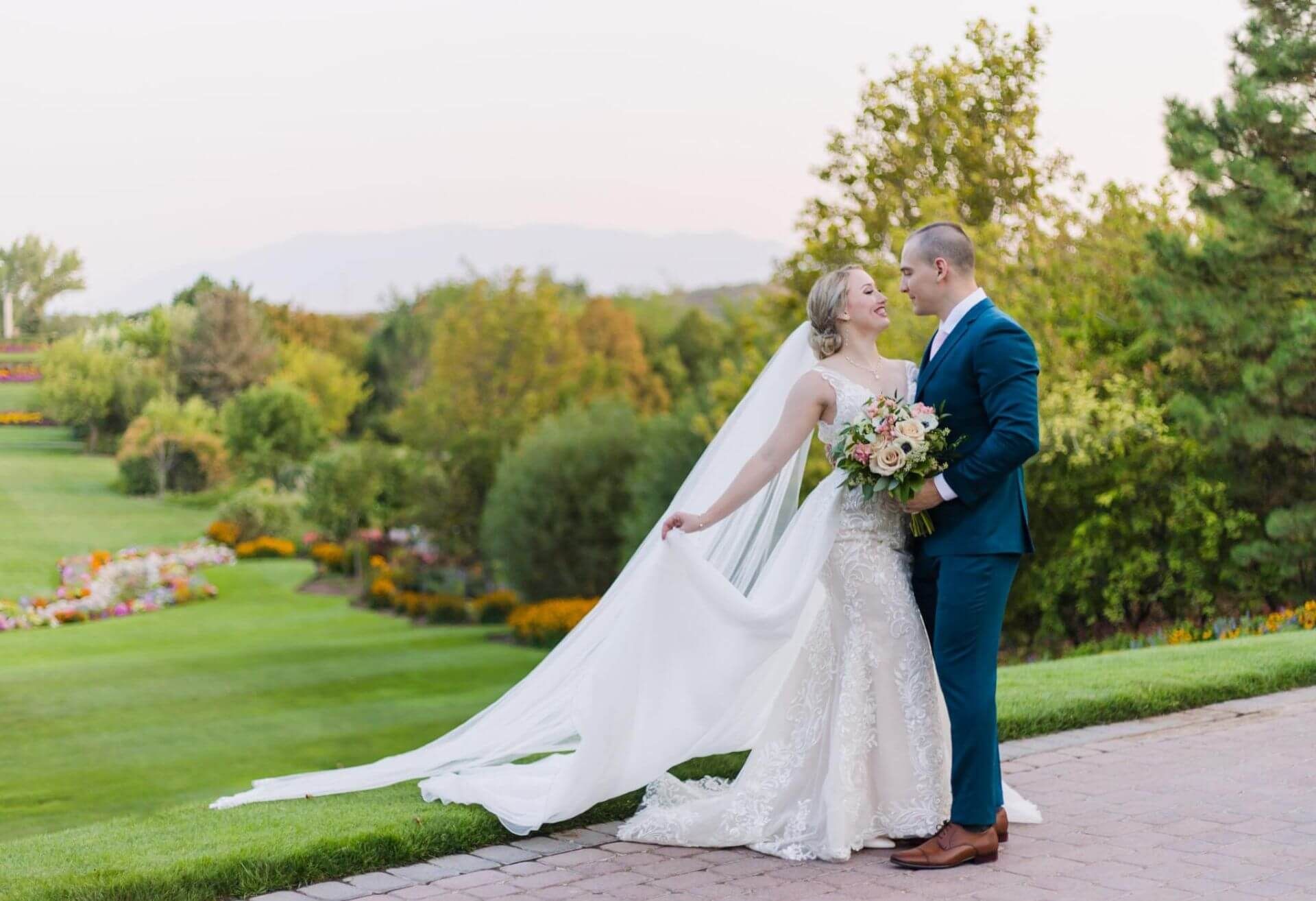 A bride and groom are posing for a picture on their wedding day . the bride is wearing a long veil.