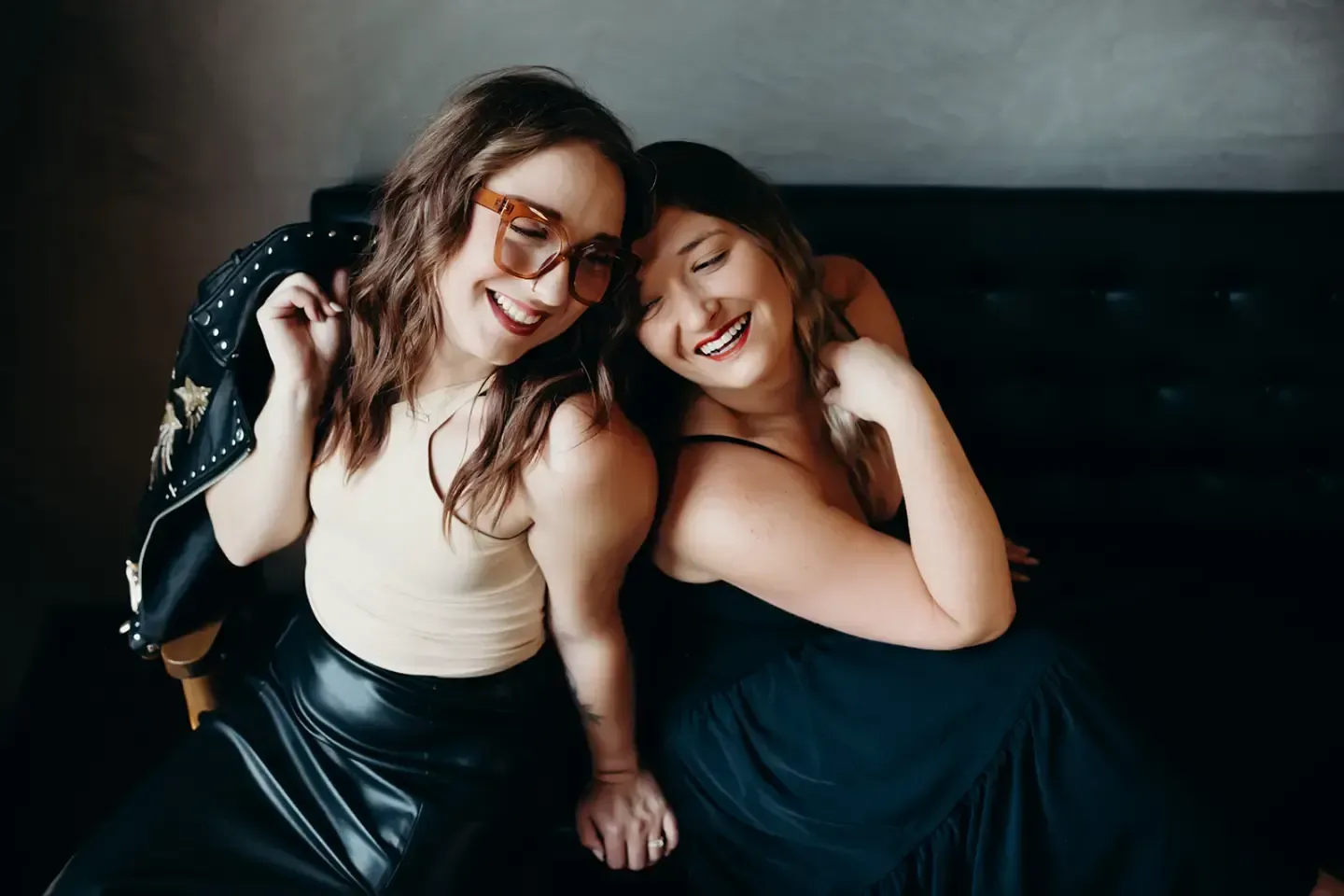 Two women are sitting next to each other on a couch.