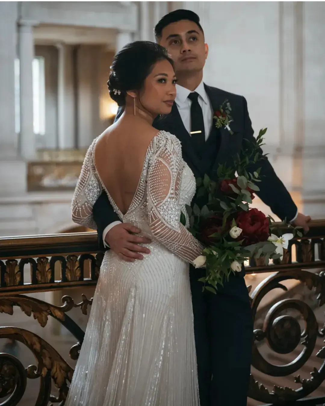 A bride and groom are posing for a picture on a balcony.