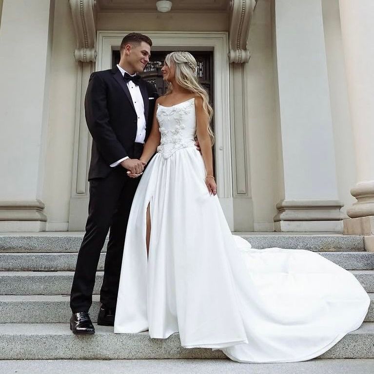 A bride with a custom Elizabeth Lee basque waist bridal gown and her groom posing for a picture on the steps of a building