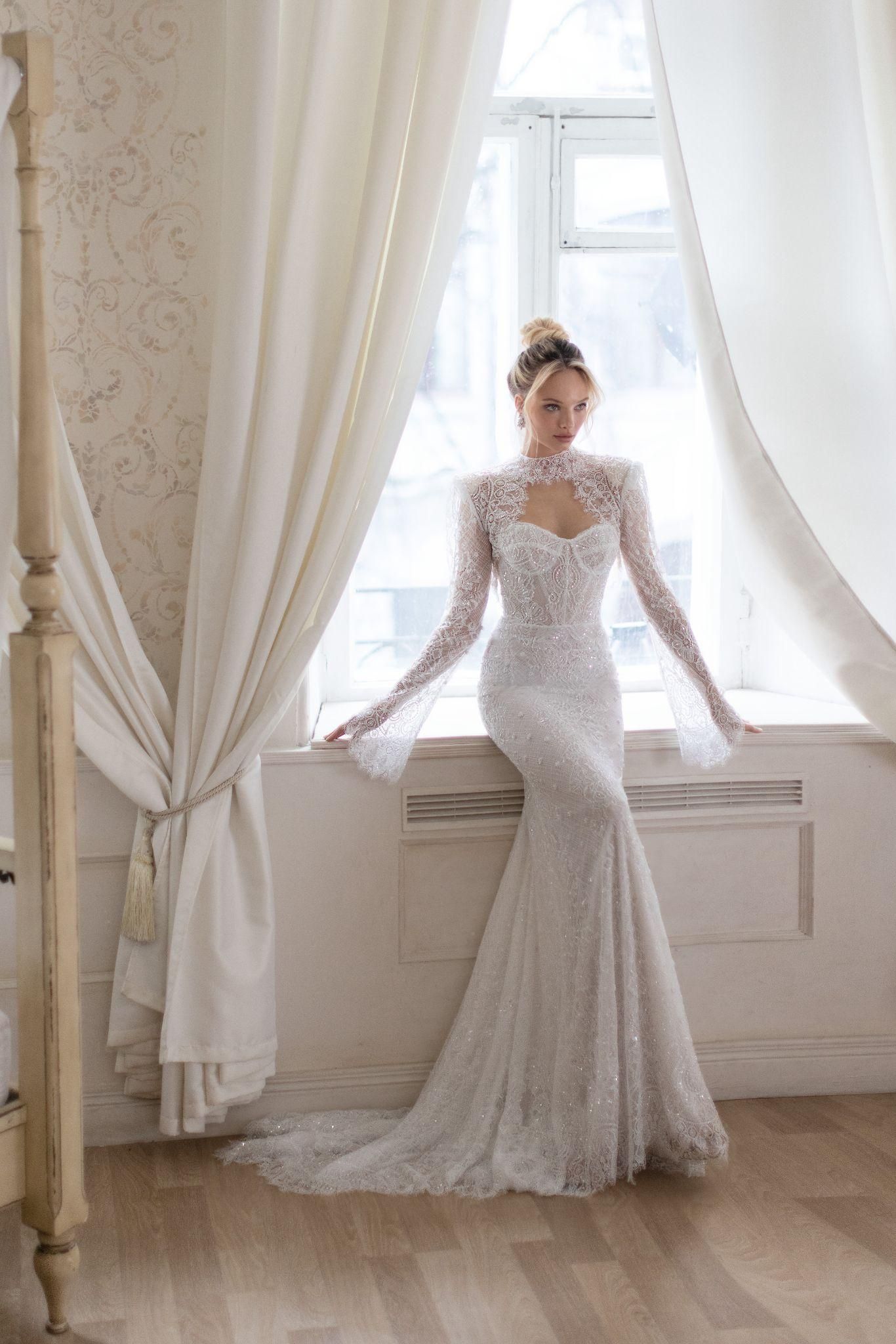 A woman in a wedding dress is sitting on a window sill.