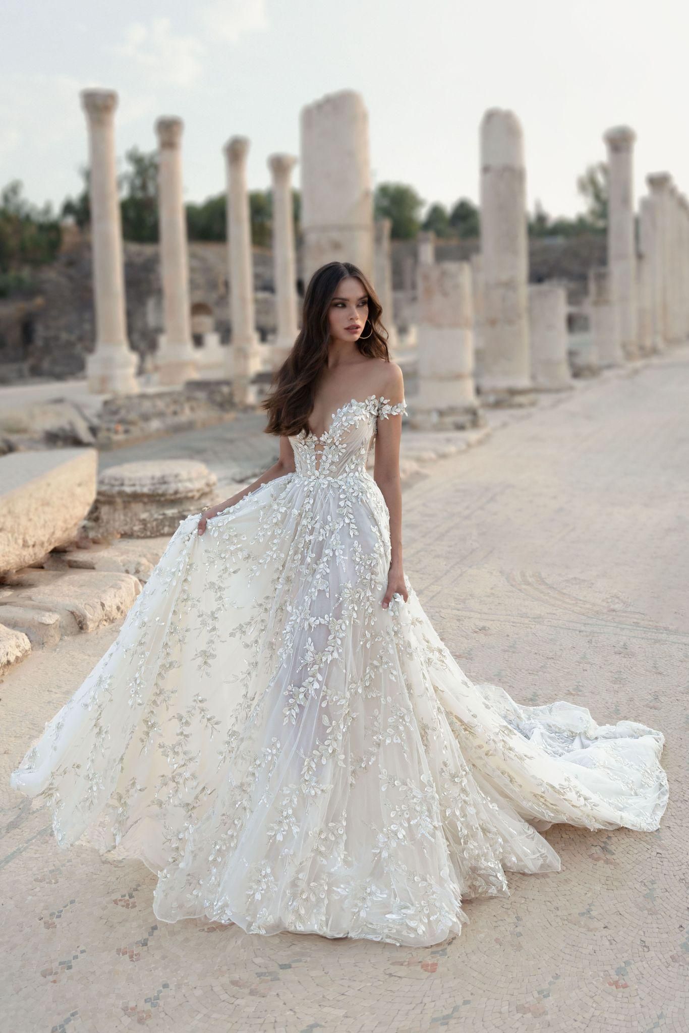 A woman in a wedding dress is standing in front of a ruined building.