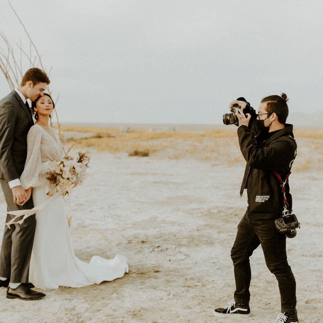 A man is taking a picture of a Utah bride and groom at the salt flats