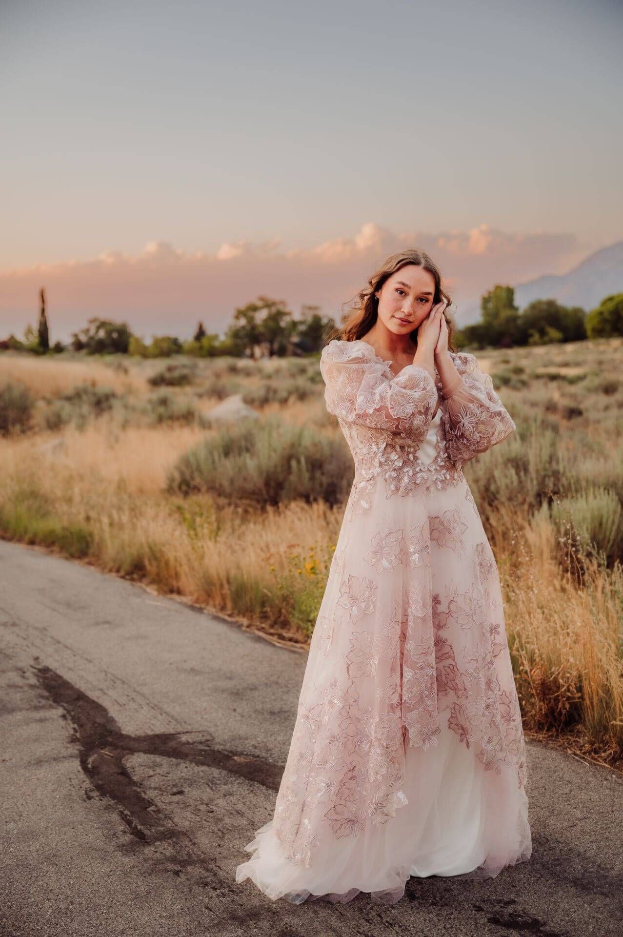 A woman in a wedding dress is standing on the side of a road.