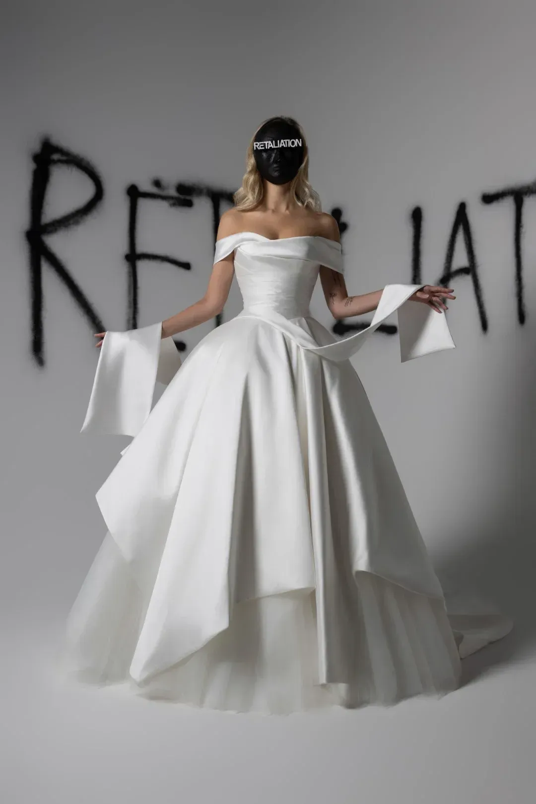 Hekate by Verander West Woman in white corset dress, dark hair, black headpiece, poses against light gray backdrop.