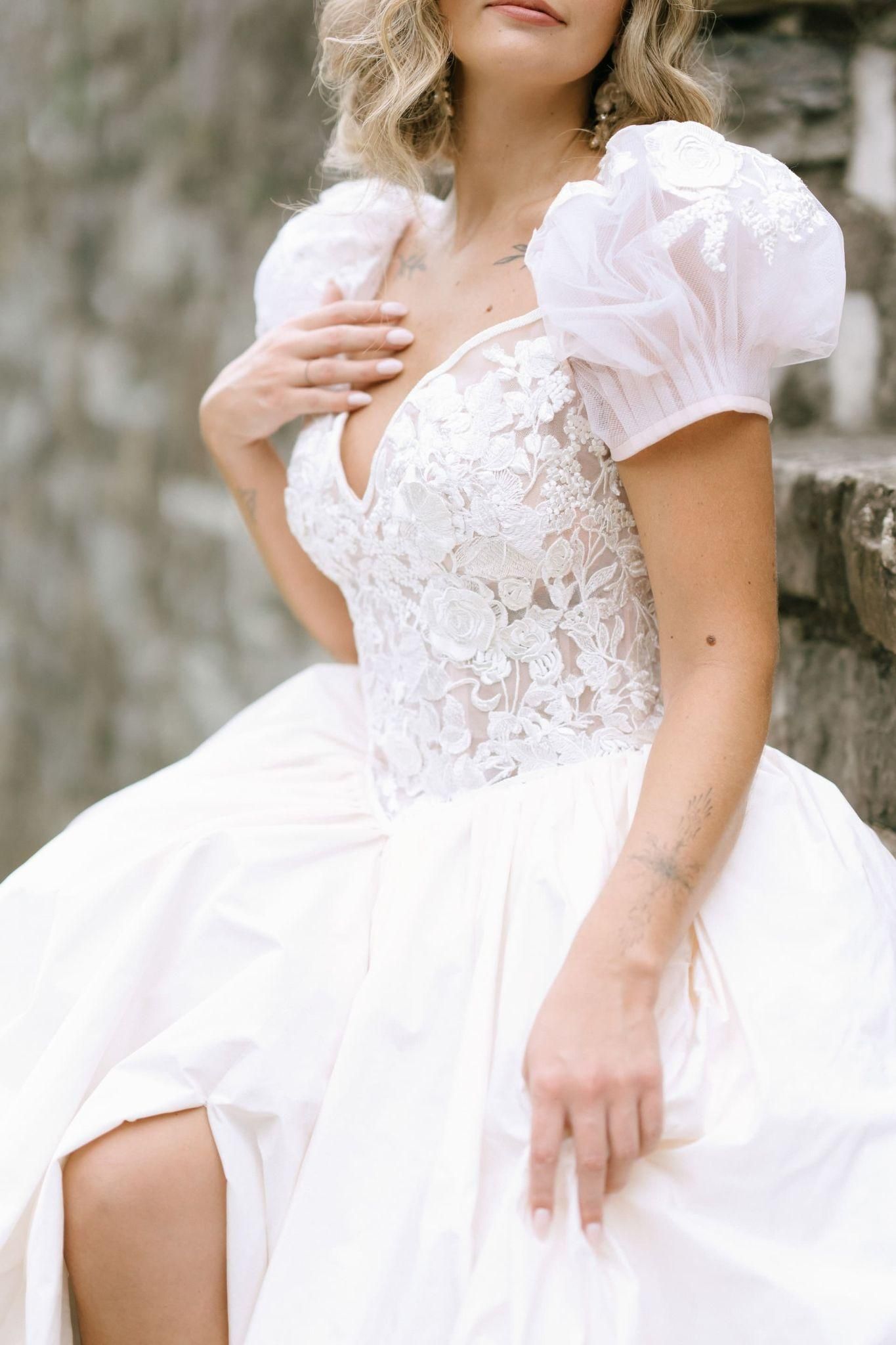 A woman in a white dress is sitting on a stone wall.