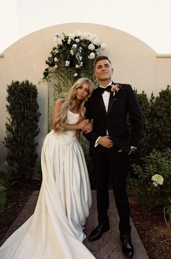 A bride and groom are posing for a picture in front of a building.