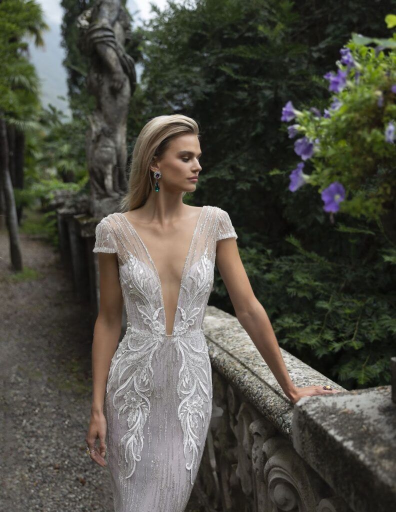 A woman in a wedding dress is leaning on a railing.