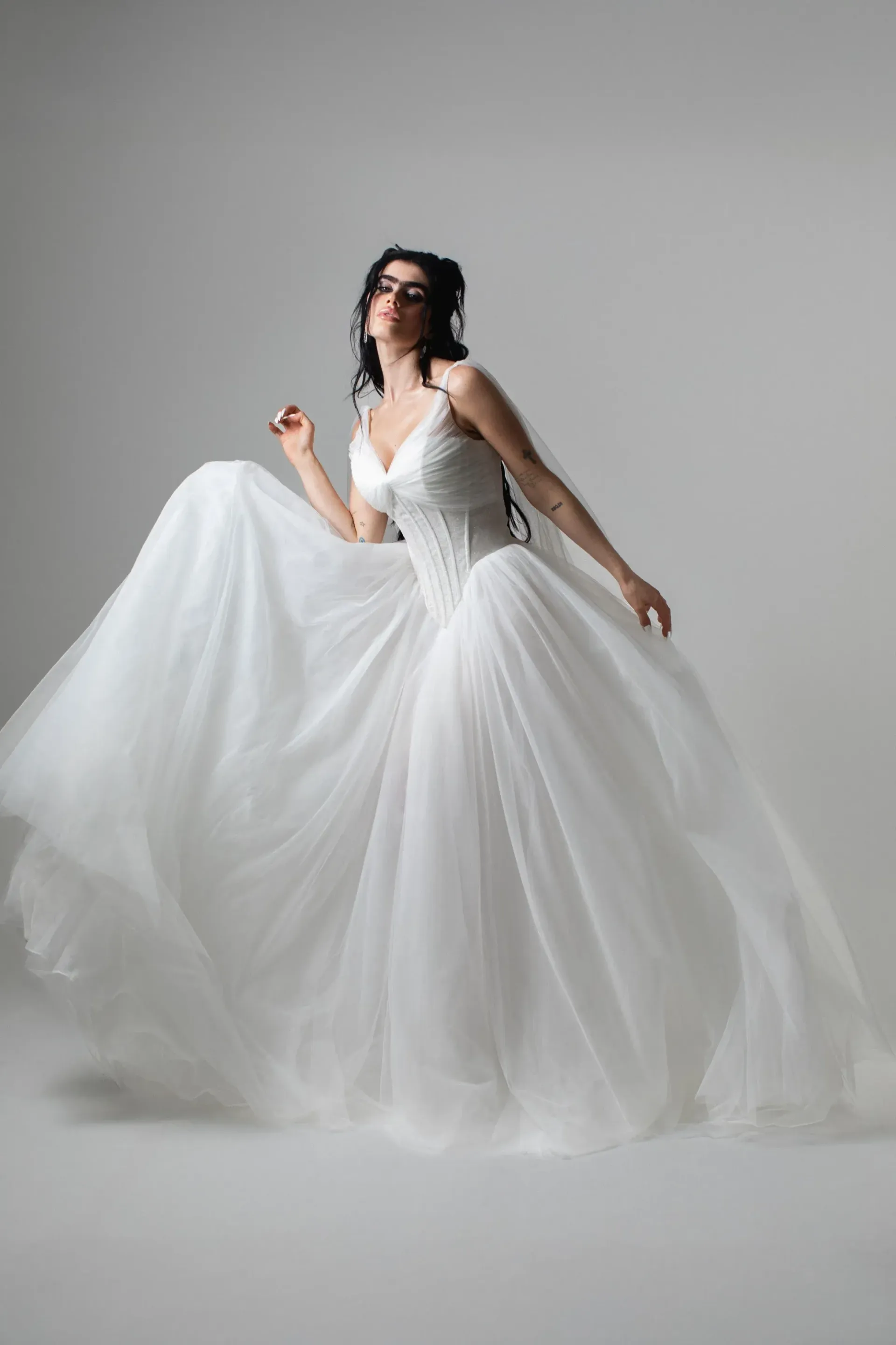 Verander West bride in a white Agnes wedding dress poses with arms outstretched, against a backdrop