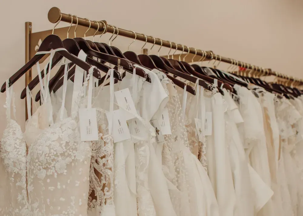 A row of wedding dresses hanging on a rack in a store.