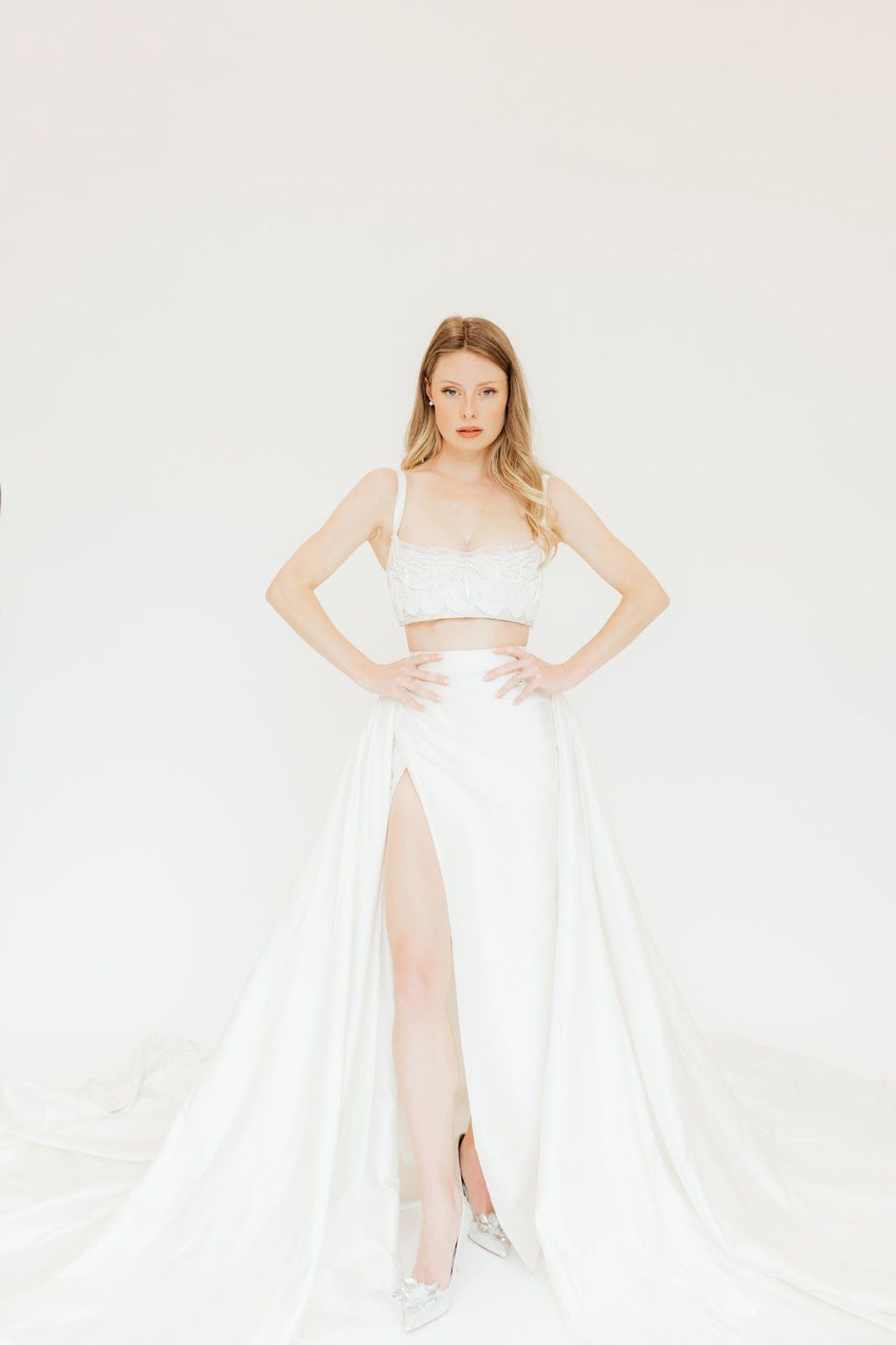 A woman is standing in a white dress with a high slit.