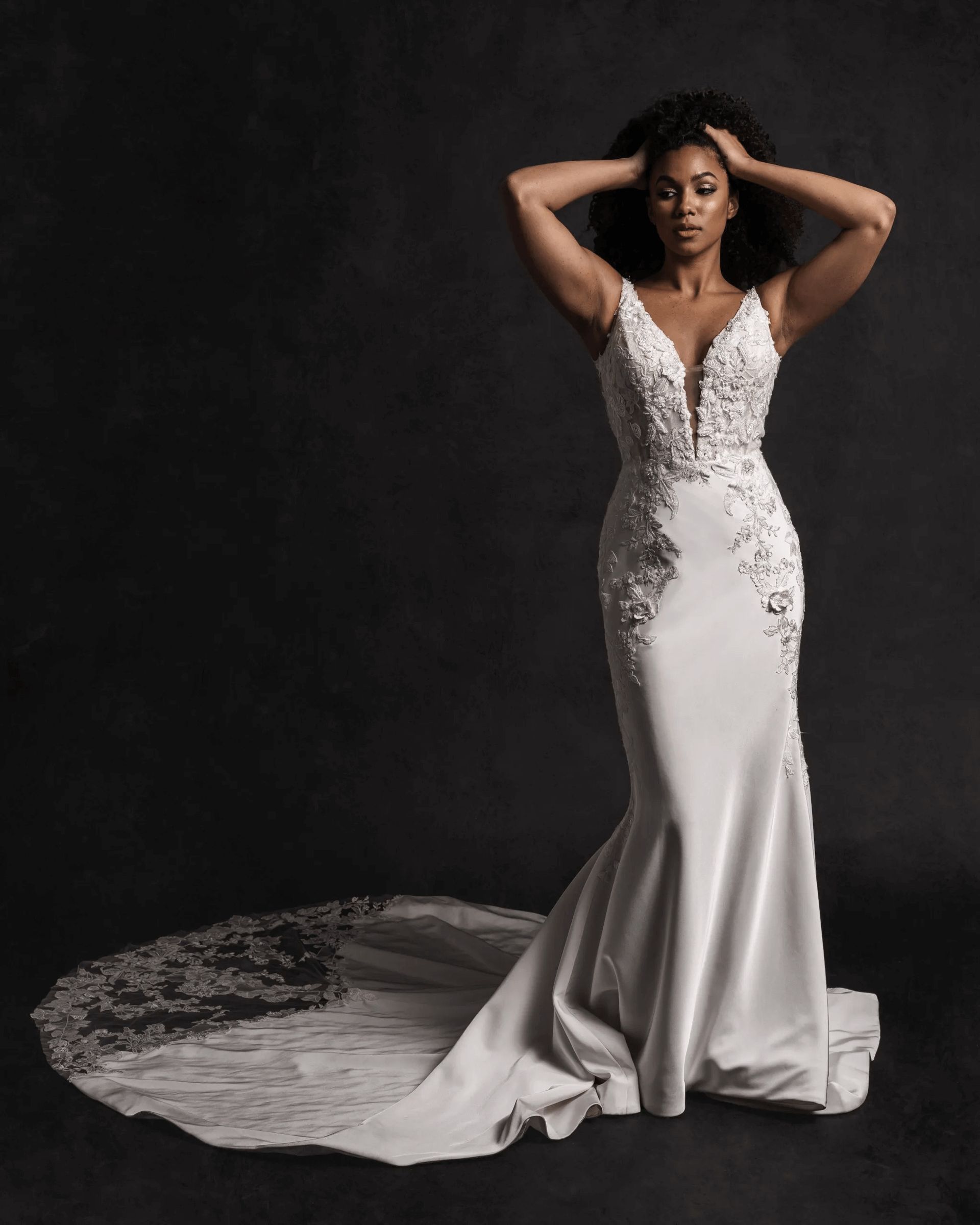 A woman in a white wedding dress is standing in front of a black background.