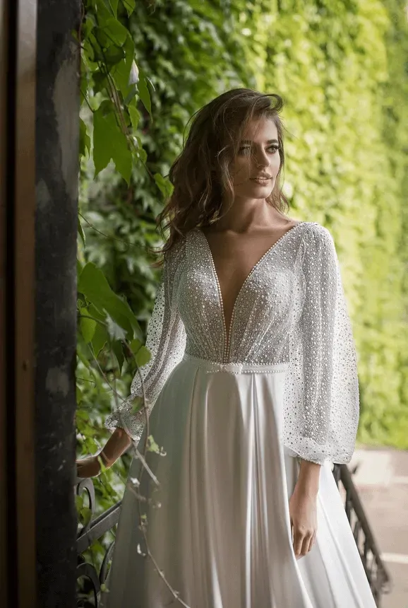 A woman in a white dress is standing in front of a green wall.