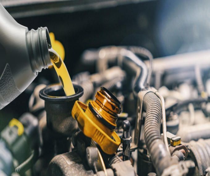 Pouring oil into a car engine, yellow oil and cap, close-up.
