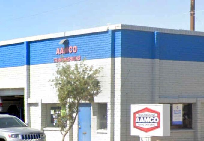 AAMCO transmission repair shop with blue and white exterior, sign, and vehicle.
