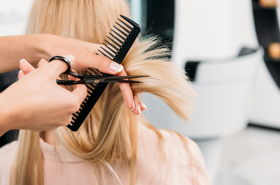 A woman is getting her hair cut by a hairdresser.
