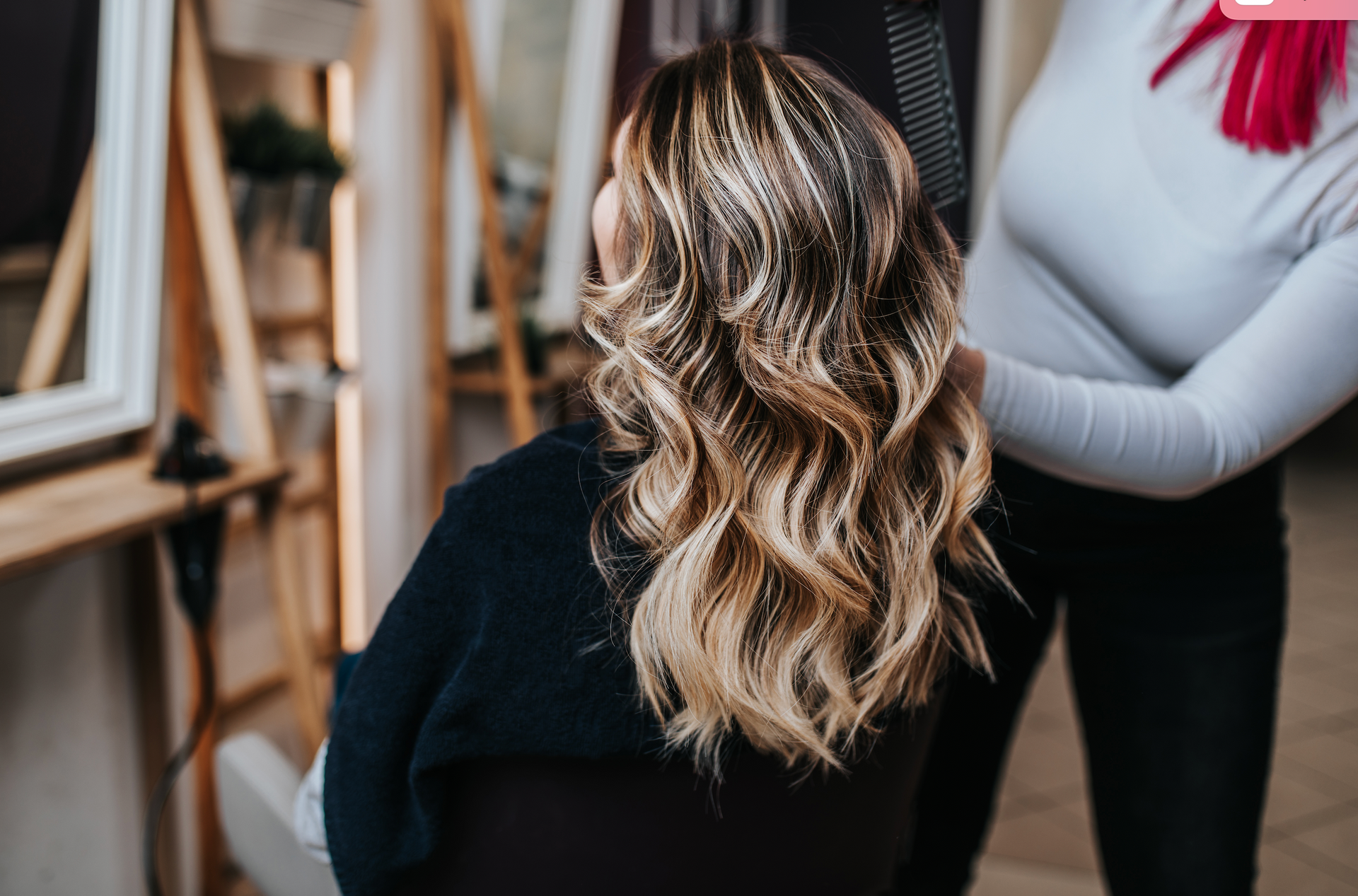 A woman is getting her hair done by a hairdresser in a salon.