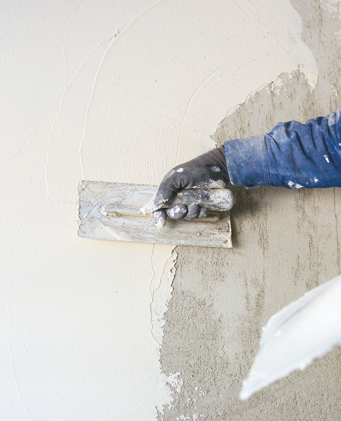 Persona che applica l'intonaco su un muro con una cazzuola.