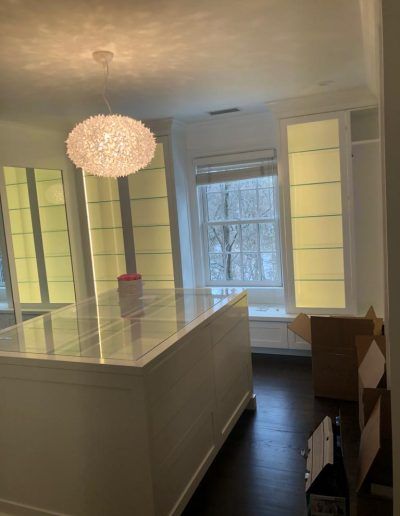 Brightly lit dressing room with white island, built-in shelving, and large window.