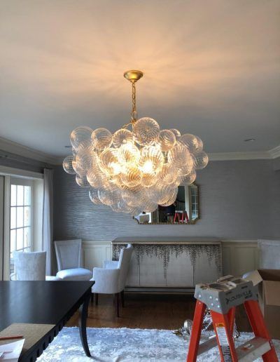 Chandelier with bubble-shaped glass globes hangs in dining room with gray walls and a buffet.